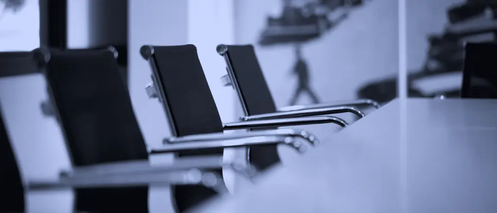 Row of empty chairs at a meeting table
