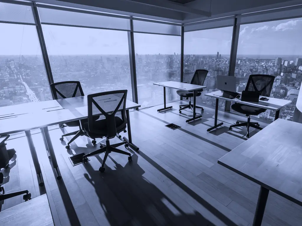 Empty office desks beside floor-to-ceiling windows