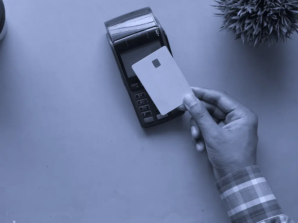 Hand holding a blank card to a card payment terminal
