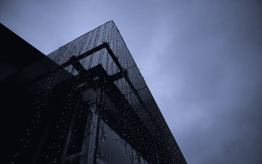 Glass corporate tower seen from below against a grey sky