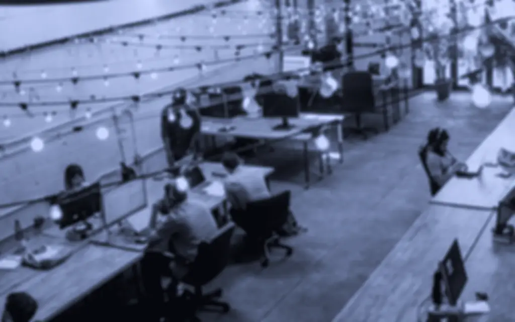 Coworking space with people working at long desks and monitors